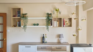 A modern living room with a wooden cabinet, bookshelves, hanging glass terrariums, and a ceiling light fixture.