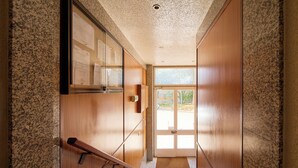 A hallway with wooden doors, a glass display case, and a view of the outdoors.
