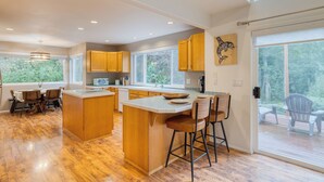 Una cocina moderna con armarios de madera, una isla grande y un comedor con sillas.