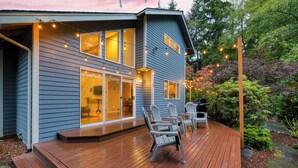 Una casa de dos pisos con un balcón, mobiliario exterior e iluminación con luces colgantes.