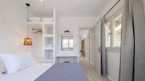 A bedroom with a bed, a wardrobe, a mirror, and a hanging light fixture. - Stone Whisper (Naxos)