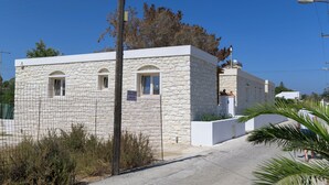 A stone building with a white facade, arched windows, and a small balcony. - Stone Whisper (Naxos)