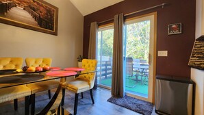 Un coin repas avec une table en verre, des chaises recouvertes d’un tissu jaune et un plateau de fruits.