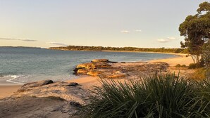 A beach with clear skies, rocky outcrops, and a sandy shoreline. - Large architect designed home directly overlooking the Royal National Park (Bundeena)