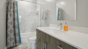 A modern bathroom with a shower, toilet, and sink.