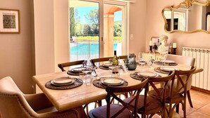 A dining area with a table set for six, a pool visible through the glass doors, and a framed picture on the wall. - Provencal house with private pool in the heart of Provence Verte - Cotignac (Cotignac)