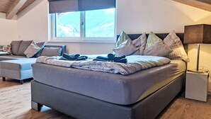 Une chambre moderne avec un grand lit, un canapé et une fenêtre donnant sur les montagnes.