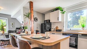Een moderne keuken met een centraal eiland, houten kasten en een groot raam.