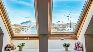Two windows with snowy landscapes and a wind turbine. - Wonderful private villa for 17 people with hot tub, WIFI, TV, patio and panoramic view (Daliburgh)