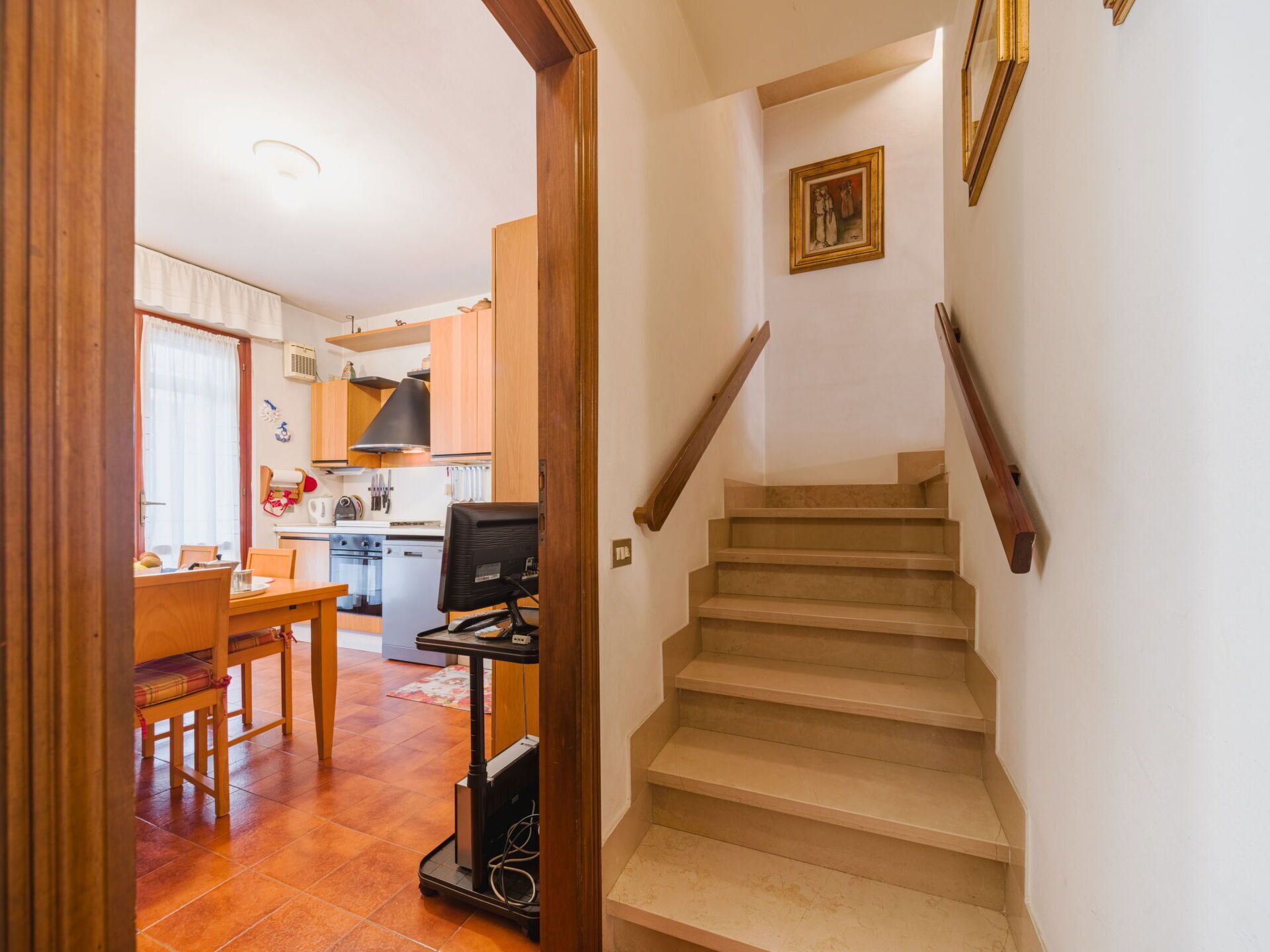 Un escalier menant à un deuxième étage, un coin repas avec une table et des chaises, et une cuisine dotée de meubles en bois et d’une cuisinière.