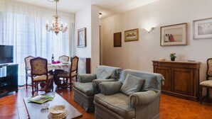 A living room with a sofa, a dining table, chairs, a TV, and a chandelier. - Wonderful  villa for 8 people with A/C, TV and patio (Viareggio)