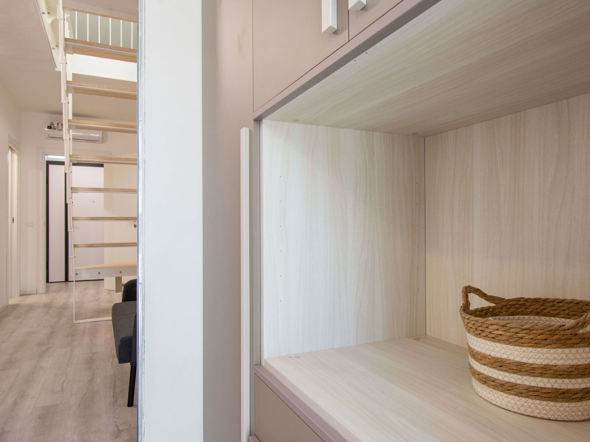 Ein modernes Zimmer mit einer eingebauten Bank, einem gewebten Korb und einer Treppe.