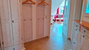 A hallway with wooden wardrobes, a red sofa, and a window with curtains.