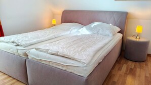 A double bed with a headboard, two bedside tables with lamps, and a wooden floor.