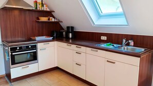A kitchen with a built-in oven, a sink, and a skylight.
