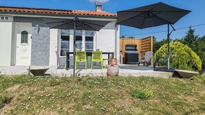 A patio area with outdoor seating, a grill, and a large umbrella.