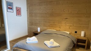Un dormitorio con paneles de madera, una cama, dos mesitas de noche y dos cuadros en la pared.