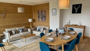 Una sala de estar moderna con piso de madera, un juego de sofá, una mesa de comedor con sillas y una zona de cocina.