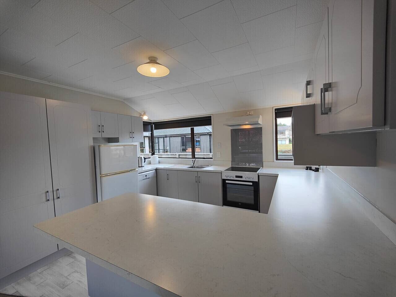 A modern kitchen with white cabinets, a large island, and a window providing natural light.