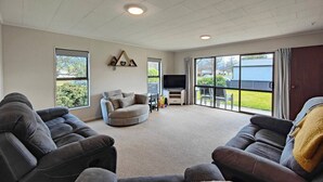 A spacious living room with a large window, a flat-screen TV, and two sofas. - Luxmore Lookout Te Anau (Te Anau)
