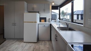 A modern kitchen with a built-in dishwasher, a sink, and a window providing a view of the outside. - Luxmore Lookout Te Anau (Te Anau)