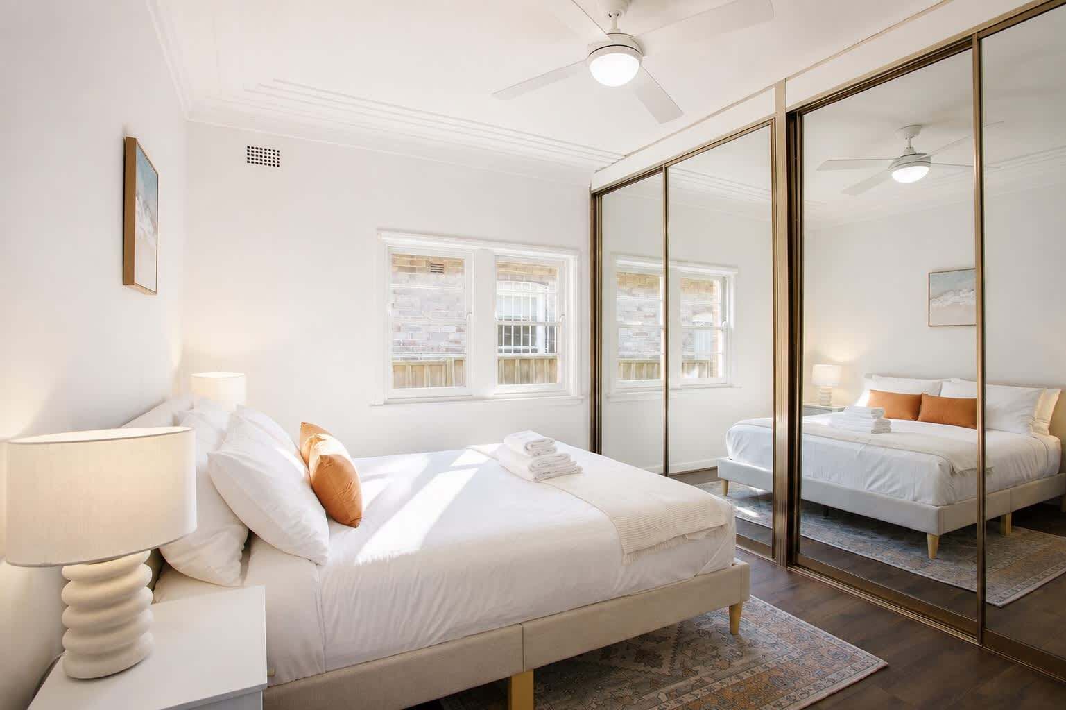 A hotel room with a bed, bedside lamp, and a large mirror.