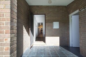 A corridor with brick walls, a tiled floor, and a door on the right.