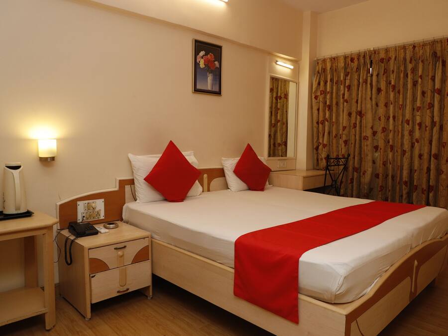 Habitación de hotel con una cama grande, una mesita de noche con lámpara, teléfono y una pequeña cómoda.