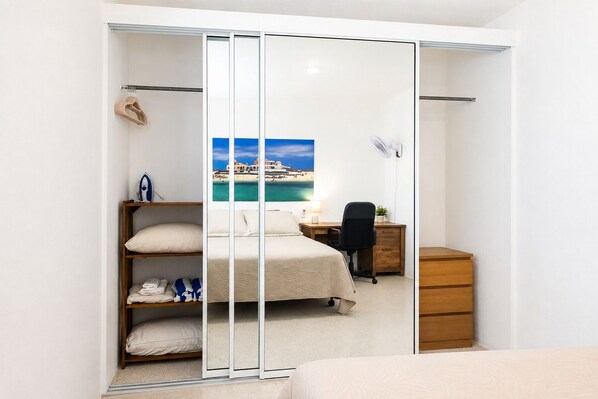 A bedroom with a bed, a desk, a chair, and a dresser.