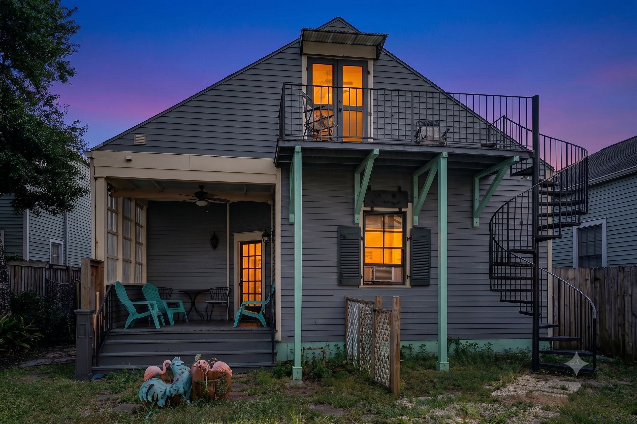 A two-story house with a covered porch, a small staircase, and a fenced yard.