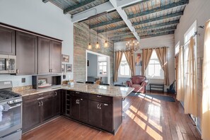 A spacious kitchen with dark wood cabinets, a granite countertop, and a large island. - Restored 4BR Creole cottage in Marigny. Sleeps 12, 2 kitchens, patio, walk to Frenchmen & FQ. (New Orleans)