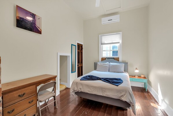 A bedroom with a bed, a desk, a chair, a window, and a painting on the wall. - Restored 4BR Creole cottage in Marigny. Sleeps 12, 2 kitchens, patio, walk to Frenchmen & FQ. (New Orleans)