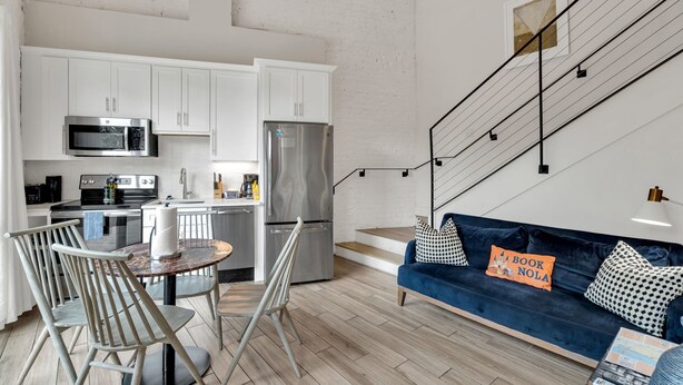 Una cocina moderna con armarios blancos, electrodomésticos de acero inoxidable y un comedor con una mesa redonda y sillas.