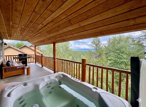Una terraza de madera con un jacuzzi, un sofá y una mesa con cojines.