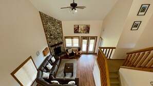 A spacious living room with a fireplace, a large sofa, and a wooden staircase. - Affordable Slope-Side: 3BR Condo w/ Private Hot Tub, Gas Fireplace, Great Location & Views. (Kimberley)