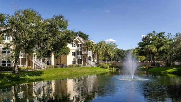 Ein Hotel mit Springbrunnen, umgeben von Bäumen und einem Teich.
