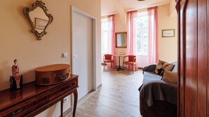 Ein Zimmer mit einem Holzkleiderschrank, einem Spiegel, einem Tisch mit Stühlen und einem Sofa.