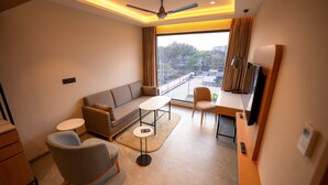 A modern hotel room with a sofa, armchair, small round table, and a TV. - 7 Apple Hotel Vizag (Visakhapatnam)