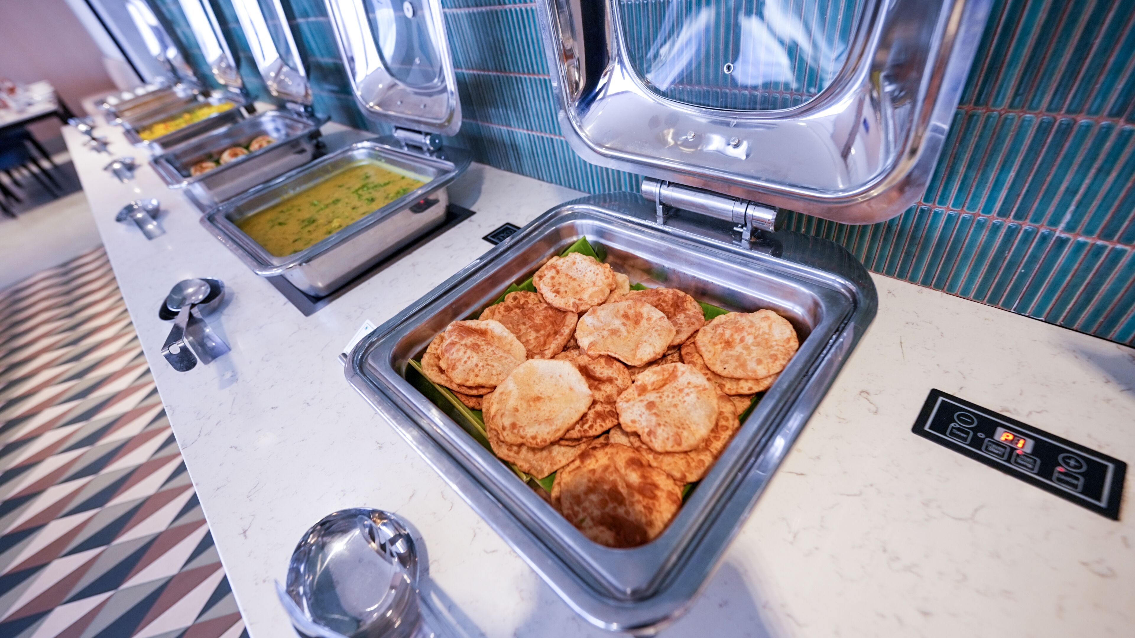 Un bufé con diversos alimentos, incluyendo una bandeja de panes planos y un tazón de sopa.