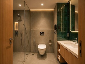 Un baño moderno con ducha de vidrio, inodoro y tocador con espejo.
