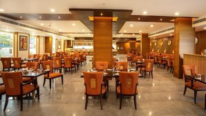 Un restaurant spacieux doté de nombreuses tables et chaises, avec un aménagement intérieur moderne agrémenté d’éléments en bois et d’une colonne centrale.