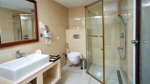 Une salle de bain moderne avec une douche à parois de verre, un lavabo blanc et un grand miroir.