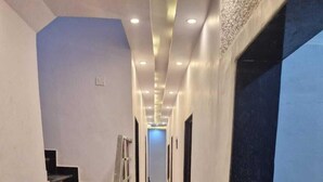 Un couloir doté d’un sol en marbre, d’un escalier noir et d’un canapé avec des coussins.