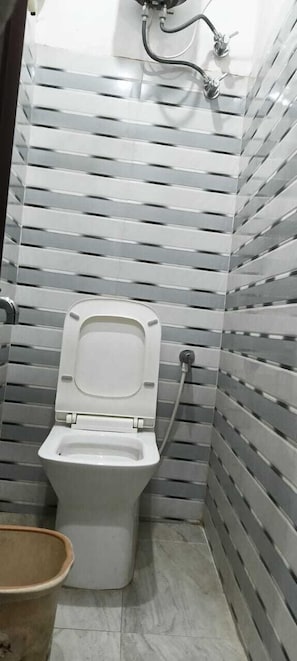 A small bathroom with a toilet, a bidet, and a trash bin.