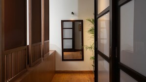 A hallway with a wooden floor, a mirror on the wall, and a potted plant. - The Nile Magical Stay! (Cairo)