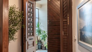 A wooden door with intricate carvings, a potted plant, and a framed picture on the wall. - The Vintage Sunshine (Cairo)