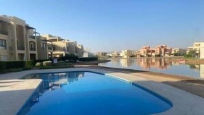 A swimming pool surrounded by residential buildings. - Sunset Haven in Tawila TownHouse (Hurghada)