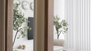 Un intérieur moderne avec un miroir à cadre en bois qui reflète une pièce comprenant un canapé blanc, une table ronde et un luminaire suspendu.