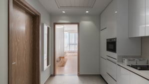 Une cuisine moderne avec des armoires blanches, un plan de travail noir et un four encastré.