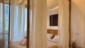 Une chambre à coucher avec un lit à baldaquin, une table de chevet et une fenêtre avec des rideaux.